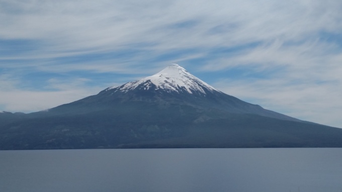 Osorno Volcano, huge volcano, topped with snow viewed across a body of water called Lago Llanquihue (Chile). 