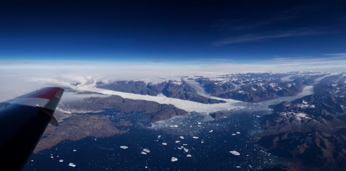 Air photo of the Helheim Glacier system in Sermilik Fjord, southeast Greenland. Poinar’s field area is at the tip of the airplane wing. Photo by Jeremy Harbeck, NASA GSFC. 