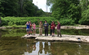 Students on a flat rock in a creek. 