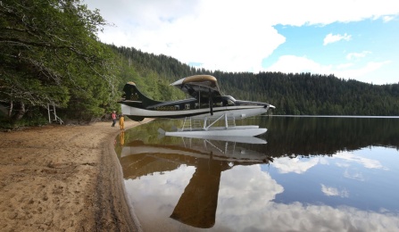 A sea plane at the edge of a lake, water like glass. 