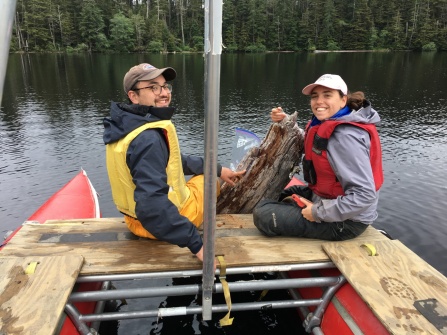 two students on a boat researching a submerged log. 