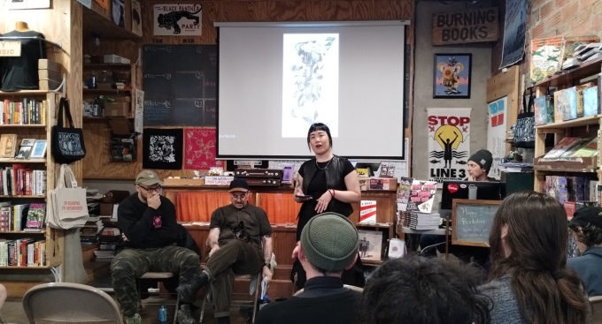 Lou Tam introducing two guest speakers, Ben Passmore and Solomon J. Brager. 