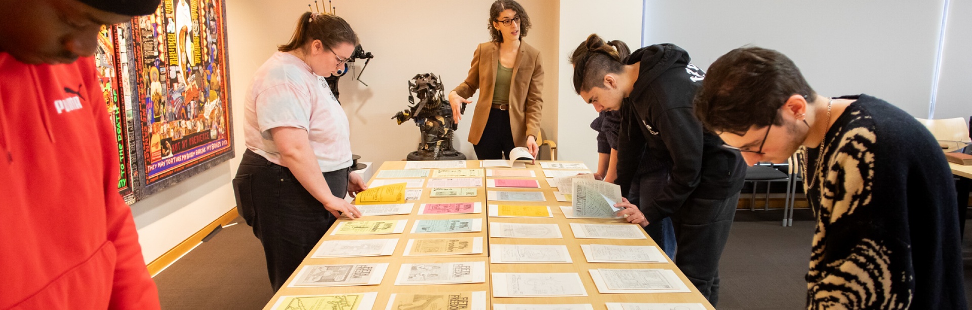 Students on an Alternative Spring Break program focused on LGBTQIA+ history and rights visit with UB Libraries&rsquo; Special Collections in Capen Hall in March 2024. The participants looked through a selection of queer publications from the Poetry Collection as well several publications of Fifth Freedom periodic newspapers. Photographer: Meredith Forrest Kulwicki. 