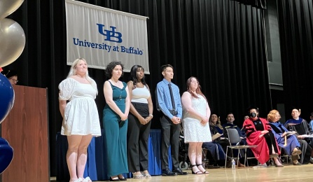 The 2023 Milton Plesur Memorial Scholarship Winners are standing on a stage for a group photo. 