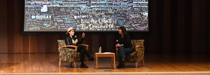 Photo of Candy Chang and Christina Milletti seated in arm chairs, in conversation on stage at the 2023 Buffalo Humanities Festival. 