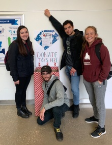 Zoom image: Students in front of toy drive donation bin.
