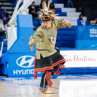 Zoom image: A man standing and dancing during a community demonstration of cultural dance.