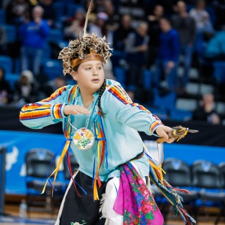 Zoom image: A young man standing and dancing during a community demonstration of cultural dance.