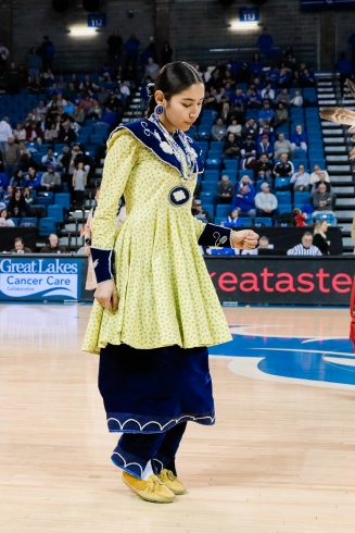 Zoom image: A woman standing and preparing to dance during a community demonstration of cultural dance.