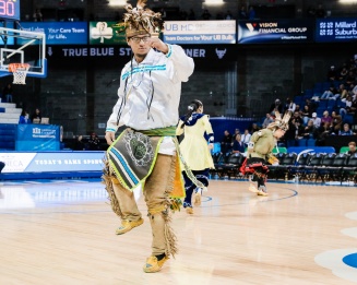 Zoom image: A man standing and dancing during a community demonstration.