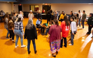 Zoom image: Group of people standing in a circle during social dance in a large room.