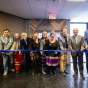 A group of people standing behind a ribbon with scissors in a lobby area. 