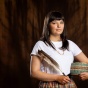 Delaney O'Connell standing in front of a wall with a feather and a basket. 