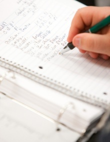 A student practices writing Hebrew in a notebook. 