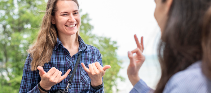 Two women communicate using sign language outdoors. 