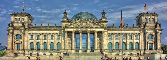 The Reichstag building in Berlin, Germany, with German flags and its glass dome. 