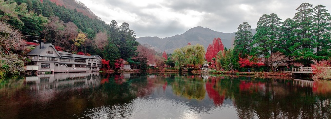 Traditional Japanese buildings and colorful autumn trees reflected in a mountain lake. 
