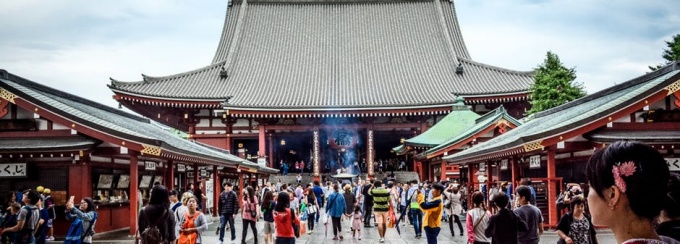 Forbidden City in Beijing. Visitors walk among traditional red buildings toward a large Japanese temple. 