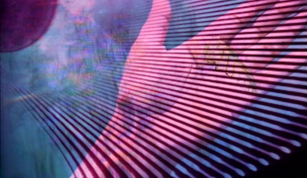 Still from Kalpana Subramanian's film 'Incantation' featuring a hand against rays of projected light. 