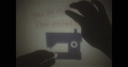 still image from film of silhouette of two hands and a sewing machine. 