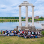 Group of international students gathered in front of the historic columns at Baird Point on UB&rsquo;s North Campus, with Lake LaSalle and campus buildings in the background. 
