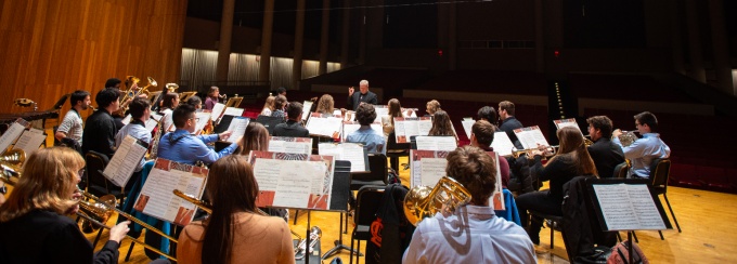 A concert band holds a dress rehearsal on the stage in Slee Hall. 
