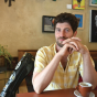 Stephen Guerra sits at a caf&eacute; table beside his instrument case. 