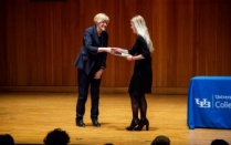Matt Reimer accepting award from the Dean of the College of Arts and Sciences on stage. 