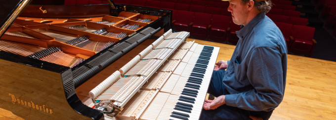 A piano technician works with the new Bösendorfer piano. 