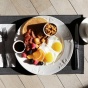 A breakfast spread with eggs, bacon, fruit and coffee. 