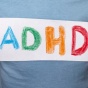 Child holding in paper that reads "ADHD" in crayon. 