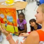 A student teacher reads a book to her class. 