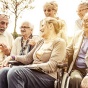 Elderly people gather on a bench. 