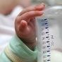 An infant's hand on a baby bottle. 