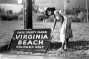 Woman stands by a "colored only" beach sign blown down during hurricane in Virginia Beach, Florida. 