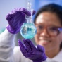 A scientist holding a vial filled with light blue liquid. 