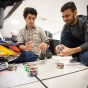 Two UB students work with small drones inside a UB lab. 