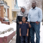 A family profiled by the project stands in front of their home, surrounded by snow. 