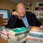 Cecil Foster sitting at a table full of books. 