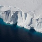 An ice shelf, bright white contrasting against dark turquoise waters. 