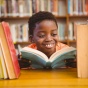 Young boy reading a book in a library. 