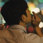  Rear view of an Asian man smoking and holding a beer bottle. 