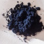 A midnight blue powder, manganese trichloride, sits on a white background. 
