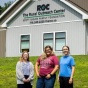 Three Social Impact Fellows student pose together in front of the Rural Outreach Center where they are working this summer. 