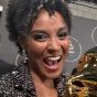 Professor Melissa White smiles, holding up a Grammy Award. 