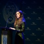 Nadia Murad standing at a podium looking out into audience giving speech with UB background. 