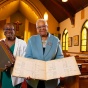 Lillian Williams and Barbara Seals Nevergold display books standing in st. Phillip's church. 