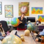 professor standing at head of table with globe, five students sitting at table listening to professor. 