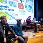 two professors sit on stage with four judges sitting in chairs. 