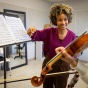 professor looking at student playing violin sitting in front of music stand with sheet music. 